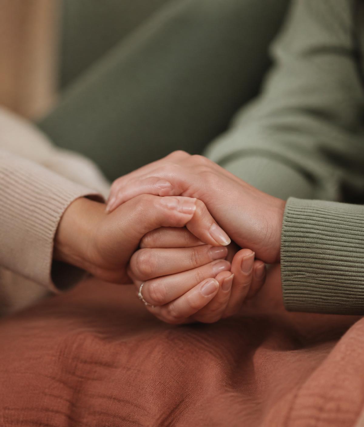Two women holding hands in a moment of quiet support